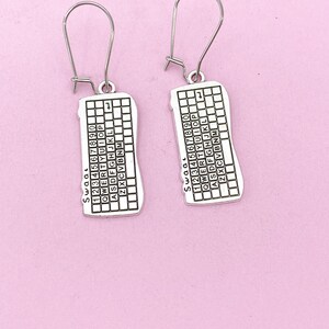 May include: A pair of silver earrings shaped like a computer keyboard. The earrings have a silver hook and the keyboard has the numbers 1234567890, the letters QWERTYUIOP, ASDFGHJKL, ZXCVBNM, and the word "SWOOL" printed on them.