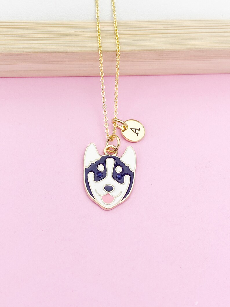 May include: Gold necklace with a black and white husky charm and a gold initial charm with the letter "A".