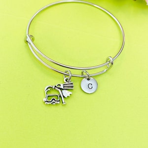 May include: A silver bangle bracelet with a charm of a skier and a silver charm with the letter C.