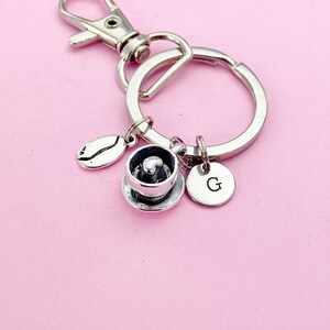 May include: Silver keychain with a coffee cup charm, a coffee bean charm, and a charm with the letter G.