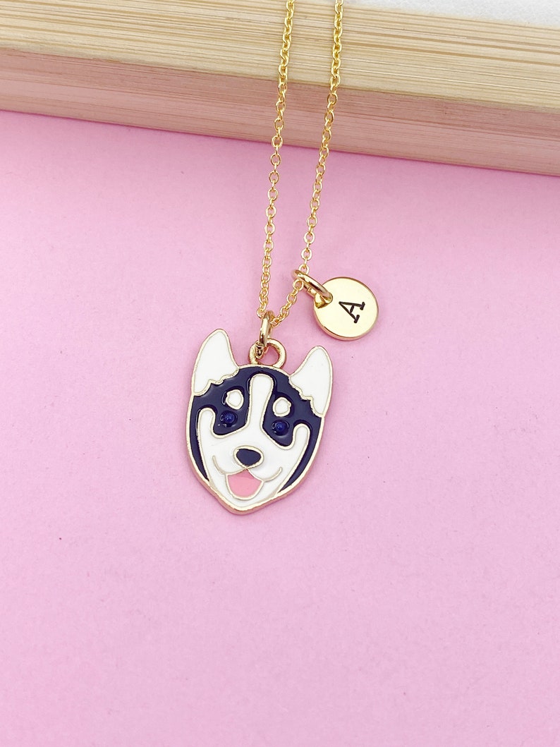 May include: A gold chain necklace with a black and white husky charm and a gold initial charm with the letter "A".