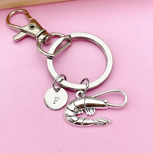 May include: Silver keychain with a silver shrimp charm and a silver disc charm with the letter 'F' engraved on it.