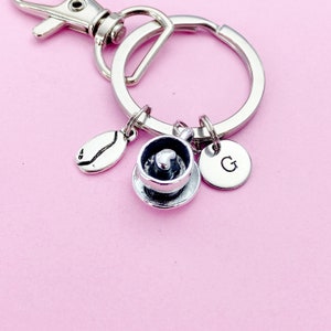 May include: Silver keychain with a coffee cup charm, a coffee bean charm, and a charm with the letter G.