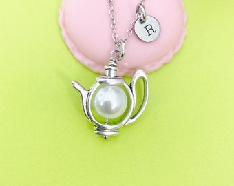 May include: A silver teapot necklace with a pearl inside. The necklace has a silver initial charm with the letter "R" on it.