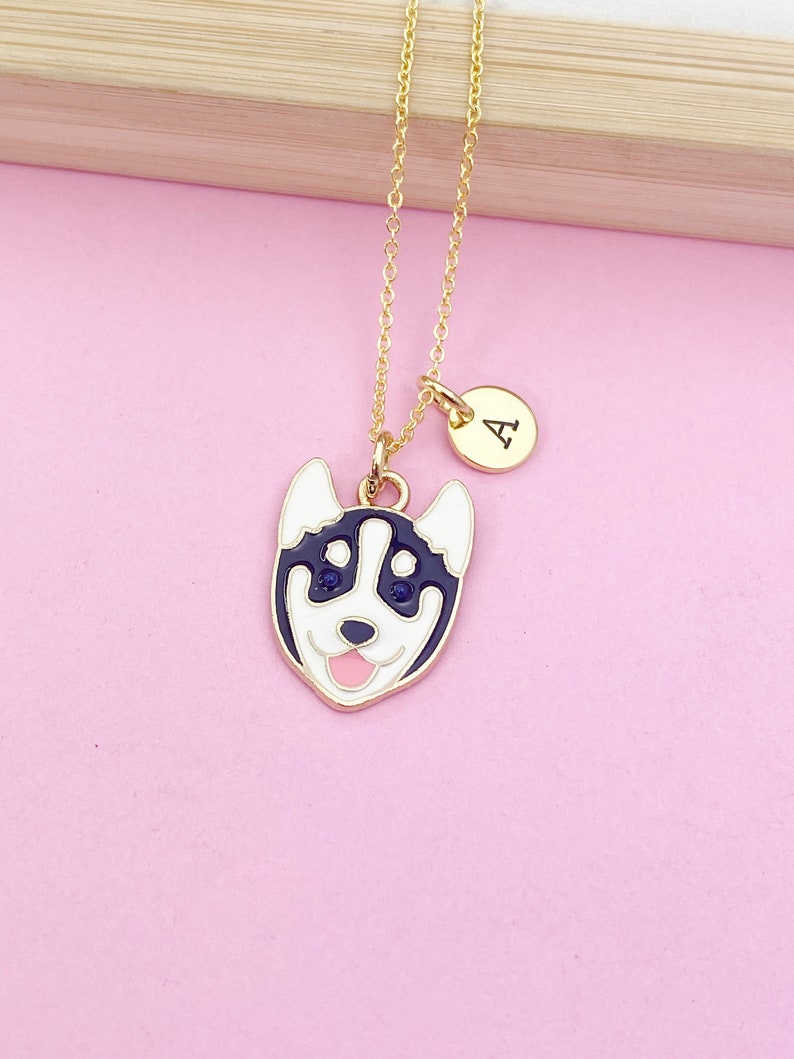 May include: A gold chain necklace with a black and white husky dog charm and a gold initial charm with the letter "A".