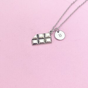May include: A silver necklace with a chocolate bar charm and a silver charm with the letter "B" on it.