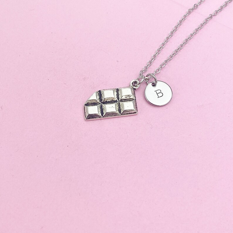 May include: A silver necklace with a chocolate bar charm and a silver charm with the letter "B" on it.