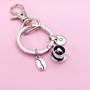 May include: Silver keychain with a coffee cup charm, a coffee bean charm, and a charm with the letter "G".