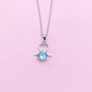 May include: A silver necklace with a blue gemstone pendant shaped like a stylized person with outstretched arms.