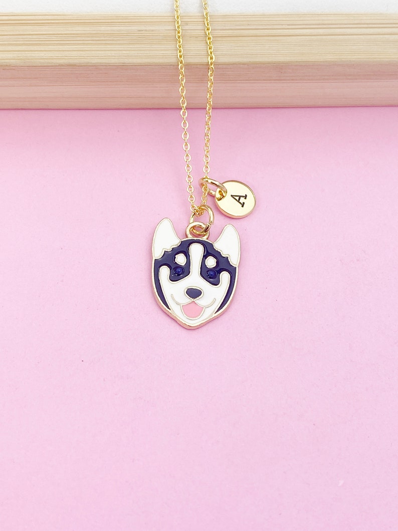 May include: Gold chain necklace with a black and white husky dog charm and a gold initial charm with the letter "A".