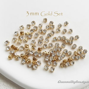 Puede incluir: Una colección de adornos de pedrería dorada de 3 mm. Los brillantes son transparentes y facetados, engastados en metal dorado. El texto "3mm Gold Set" está en la parte superior. El nombre de la tienda Etsy está en la parte inferior.