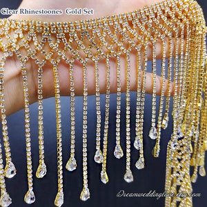 Puede incluir: Borde de flecos de cristal transparente con cadena dorada y cristales en forma de lágrima. El fleco mide aproximadamente 25 cm de largo.