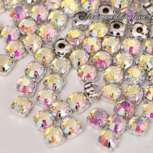 Puede incluir: Un conjunto de pedrer&iacute;a iridiscente con engastes plateados. Las piedras tienen un dise&ntilde;o redondo y facetado que refleja m&uacute;ltiples colores. La imagen incluye el texto "dreamweddinglove.etsy.com".