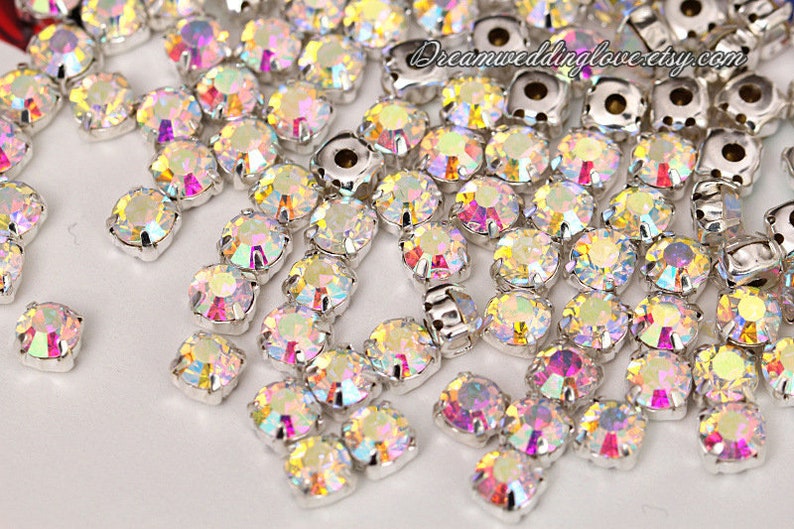 Puede incluir: Un conjunto de pedrer&iacute;a iridiscente con engastes plateados. Las piedras tienen un dise&ntilde;o redondo y facetado que refleja m&uacute;ltiples colores. La imagen incluye el texto "dreamweddinglove.etsy.com".