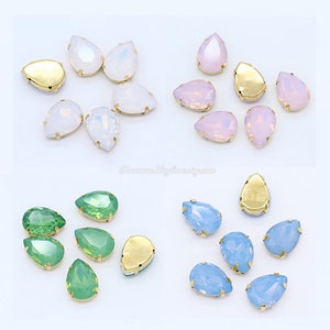 Peut inclure: Assortiment de strass en verre en forme de goutte avec des montures dorées. Les strass sont disponibles en différentes couleurs, notamment le blanc, le rose, le vert et le bleu.