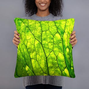 May include: A square throw cushion featuring a vibrant, high-resolution print of a bright green leaf with detailed, dark green veins. The surface displays a natural, organic texture with varying shades of lime and emerald green throughout the pattern.