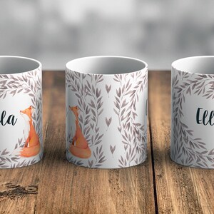May include: Three white ceramic mugs with a grey and white leafy design and a fox illustration. The mugs have the name "Ella" printed on them.