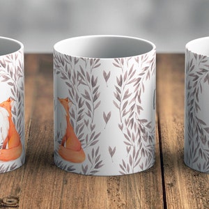 May include: Two white ceramic mugs featuring a watercolour design of grey leaves and a fox. The mugs are personalised with the name "Ella" printed on them.