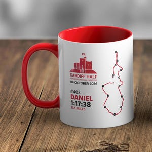 May include: A white ceramic mug with a red interior and handle, featuring a red graphic of a castle, the text Cardiff Half, Hanner Marathon Caerdydd, 04 October 2026, #403, Daniel, 1:17:38, 13.1 miles, and a red line map of a race route.
