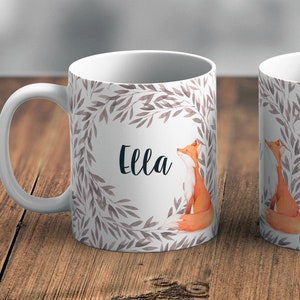 May include: White ceramic mug featuring a watercolour design of a fox and leaves. The mug is personalised with the name "Ella".