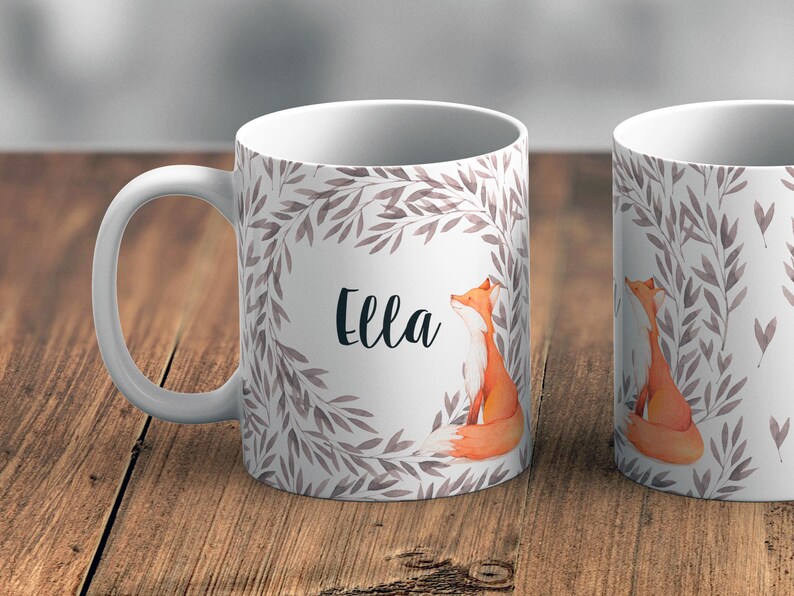 May include: White ceramic mug featuring a watercolour design of a fox and leaves. The mug is personalised with the name "Ella".