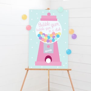 May include: A pink gumball machine illustration with the text "Bubble gum, bubble gum, in a dish" on a light blue background with white polka dots. Colorful gumballs fill the machine's globe. The image is displayed on a wooden easel.