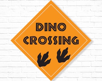 May include: Orange diamond-shaped sign with black text that reads "Dino Crossing" and two black dinosaur footprints.
