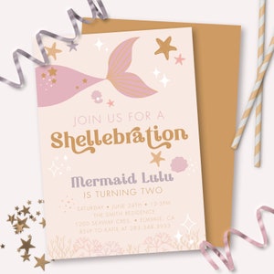 May include: A light pink invitation with a mermaid theme. The invitation reads "Join us for a Shellebration" and "Mermaid Lulu is turning two." The design includes a mermaid tail, stars, and seashells. A gold envelope and decorative straws are also present.