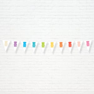Op de afbeelding: Een witte slinger met een patroon van kleurrijke gummy bear vormen. De gummy bears zijn in verschillende kleuren, waaronder geel, paars, blauw, groen, oranje en roze. De slinger hangt tegen een witte bakstenen muur.