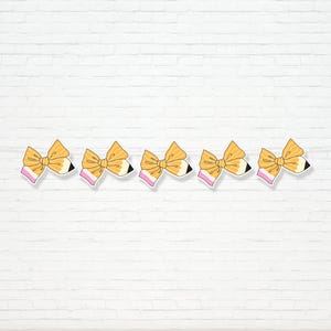 Könnte beinhalten: Fünf Bleistift-Bogen-Aufkleber. Jeder Aufkleber zeigt eine gelbe Schleife mit einem rosa Akzent und einem schwarz-weißen Bleistiftspitzendesign. Die Aufkleber sind in einer Reihe vor einer weißen Backsteinmauer angeordnet.
