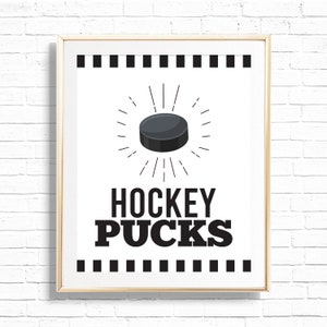 May include: A black and white printable wall art design with a hockey puck graphic and the text "HOCKEY PUCKS".