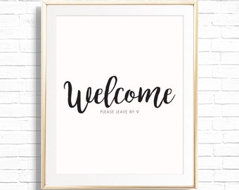 May include: A framed print with the word "Welcome" in a black script font. Below the word "Welcome" is the text "PLEASE LEAVE BY 9" in a smaller font. The frame is gold, and the background is white.