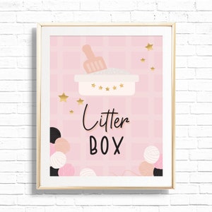 May include: A pink and white sign with gold stars and the text "Litter Box" in black script. The sign features a cartoon illustration of a pink litter box with a scoop and white litter.