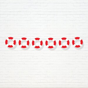 May include: A string of six red and white life preserver decorations hanging against a white brick wall.