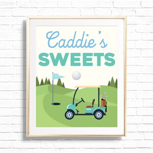 Puede incluir: Una impresión enmarcada con el texto "Caddie's Sweets" en letras azules y verdes. La impresión presenta un carro de golf de dibujos animados en un campo de golf verde con una bandera y una pelota de golf en el aire.