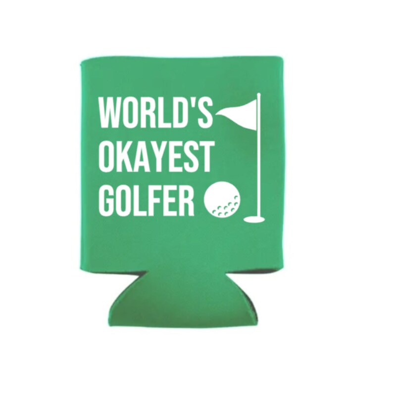 Op de afbeelding: Groene koelbox voor blikjes met de tekst "WORLD'S OKAYEST GOLFER" in wit. Een witte golfbal en vlag bevinden zich aan de rechterkant van de koelbox.