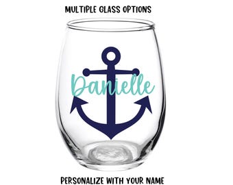 May include: A clear stemless wine glass with a navy blue anchor design and the name "Danielle" in teal script. The text "MULTIPLE GLASS OPTIONS" and "PERSONALIZE WITH YOUR NAME" are also visible.