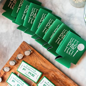 May include: A stack of green and white golf-themed beverage insulators with the text "Let's Par Tee!" printed on them. A golf ball and club are pictured on the top insulator.