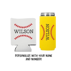 May include: Two personalized can coolers with a baseball stitch design. The cooler on the left is white with red stitching and the cooler on the right is yellow with red stitching. Both coolers have the name "WILSON" printed on them.