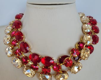 May include: A gold tone statement necklace with large red and clear faceted crystal stones. The necklace is layered with two rows of crystals.