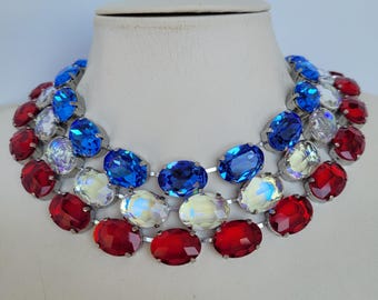 Peut inclure: Un collier en chaîne argentée avec trois rangées de strass ovales. Les strass sont rouges, blancs et bleus, créant un motif de couleurs patriotiques.