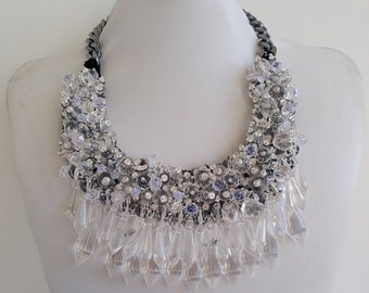 May include: A silver and clear crystal statement necklace with a chunky chain and a cascading fringe of crystals.
