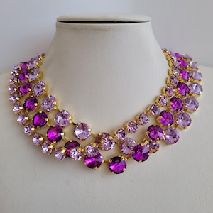 Puede incluir: Un collar de varias capas con piedras de cristal de color morado y rosa engastadas en oro.