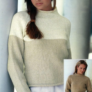 May include: A two-tone knitted sweater with a high neck and long sleeves. The sweater is white on top and beige on the bottom.