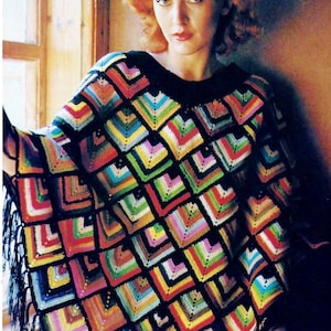 Könnte beinhalten: Ein farbenfrohes Häkelponcho mit geometrischem Muster. Das Poncho ist aus verschiedenen Farben gefertigt, darunter Rot, Grün, Blau, Gelb und Orange. Das Poncho hat einen Fransenrand.