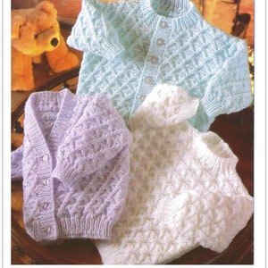 May include: Three knitted baby cardigans in different colors: light blue, lavender, and white. The cardigans have a button-up front and a diamond-shaped stitch pattern.