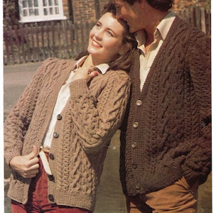 Puede incluir: Una pareja lleva cárdigans de punto de cable marrón. La mujer lleva pantalones de pana rojos y el hombre lleva pantalones de pana marrones.