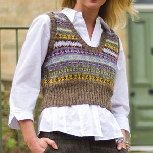 May include: A brown knitted vest with a colorful geometric pattern. The vest has a V-neck and is cropped.