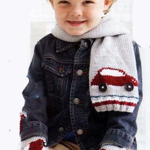 Könnte beinhalten: Ein kleines Kind trägt einen grauen Strick Schal mit einem roten Auto-Design und passende Strick-Handschuhe mit roten Auto-Designs. Das Kind trägt auch eine Jeansjacke und eine braune Hose.