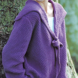 May include: A purple knitted cardigan with a large collar and a tie at the front. The cardigan is made with a textured stitch.
